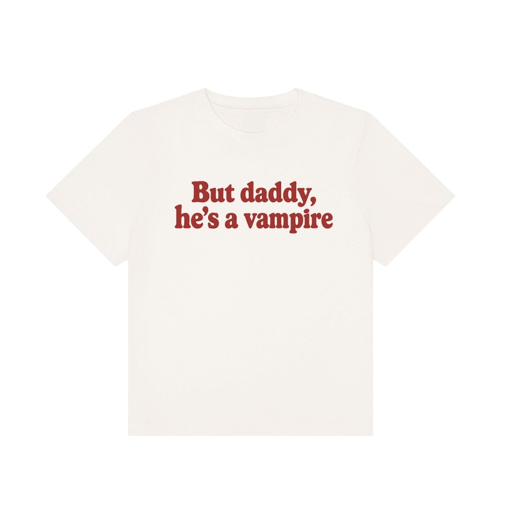An off-white short-sleeve t-shirt with the phrase 'But daddy, he's a vampire' printed in red serif text across the chest, displayed on a solid white background.