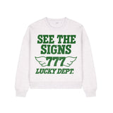 White sweatshirt with green text 'See the Signs 777 Lucky Dept.' on a white background