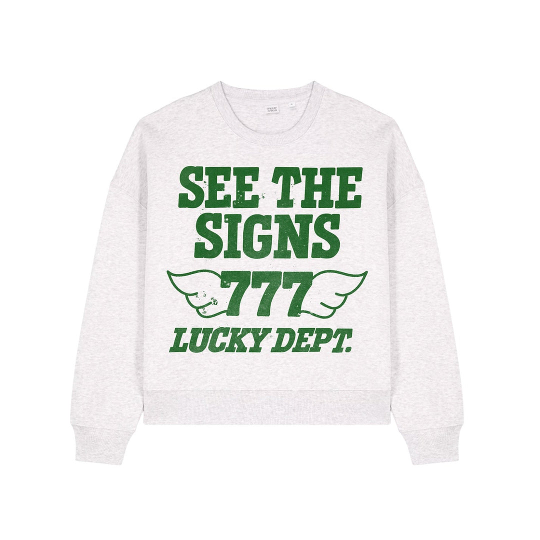 White sweatshirt with green text 'See the Signs 777 Lucky Dept.' on a white background